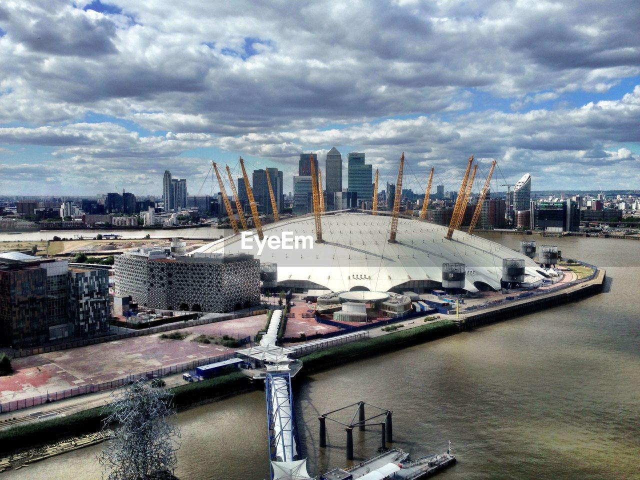 High angle view of millennium dome by river against cloudy sky