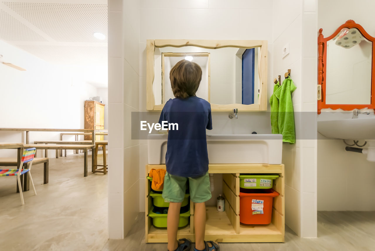 REAR VIEW OF GIRL STANDING IN HOME