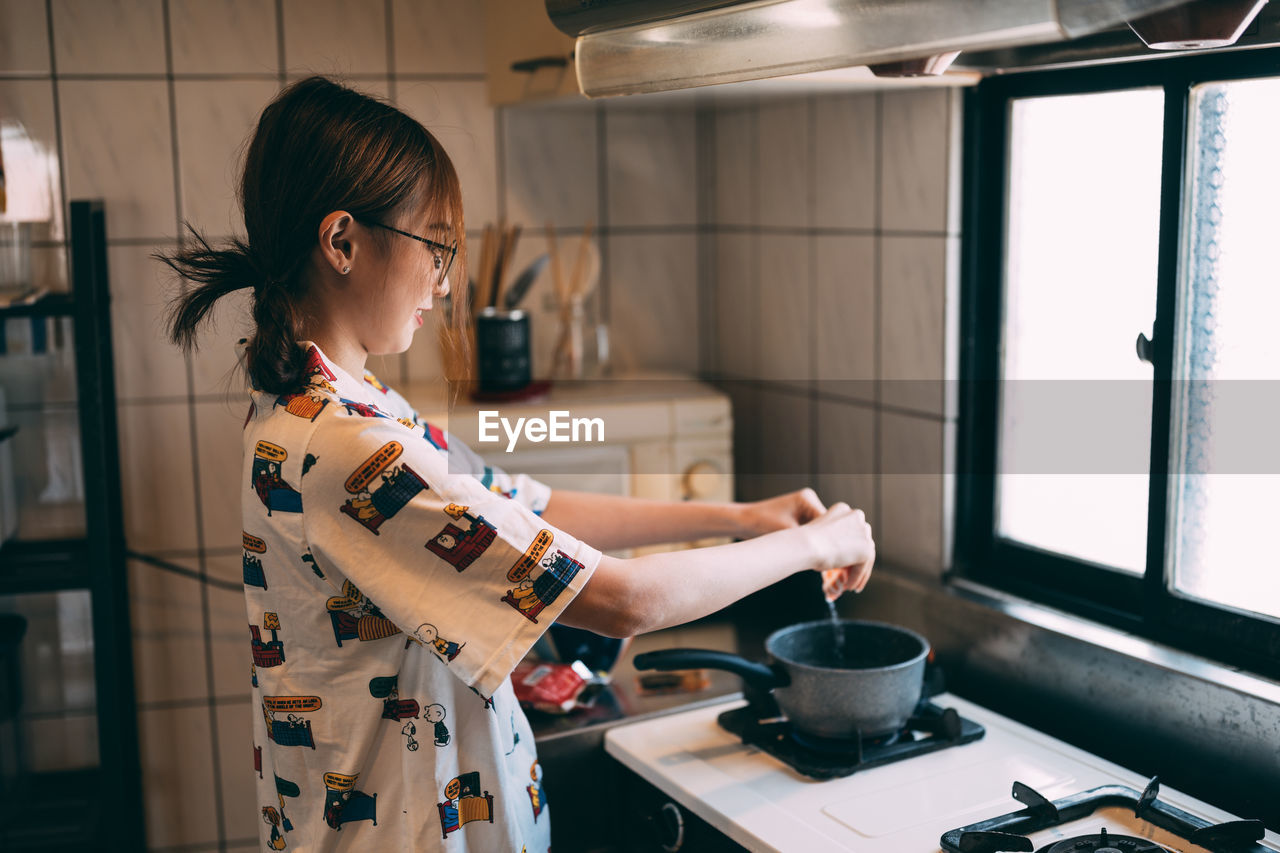 side view of young woman using mobile phone at home