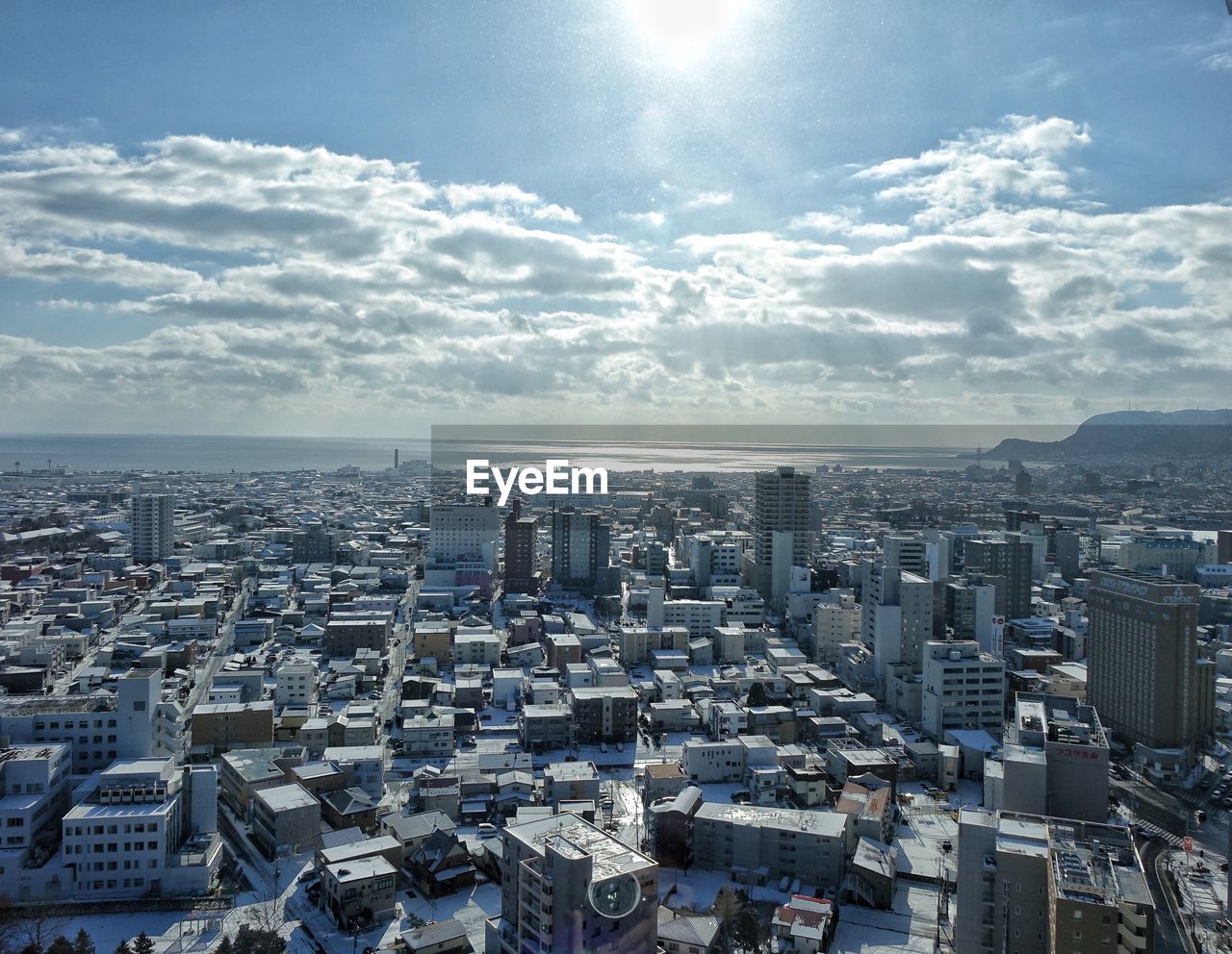 Aerial view of city against cloudy sky