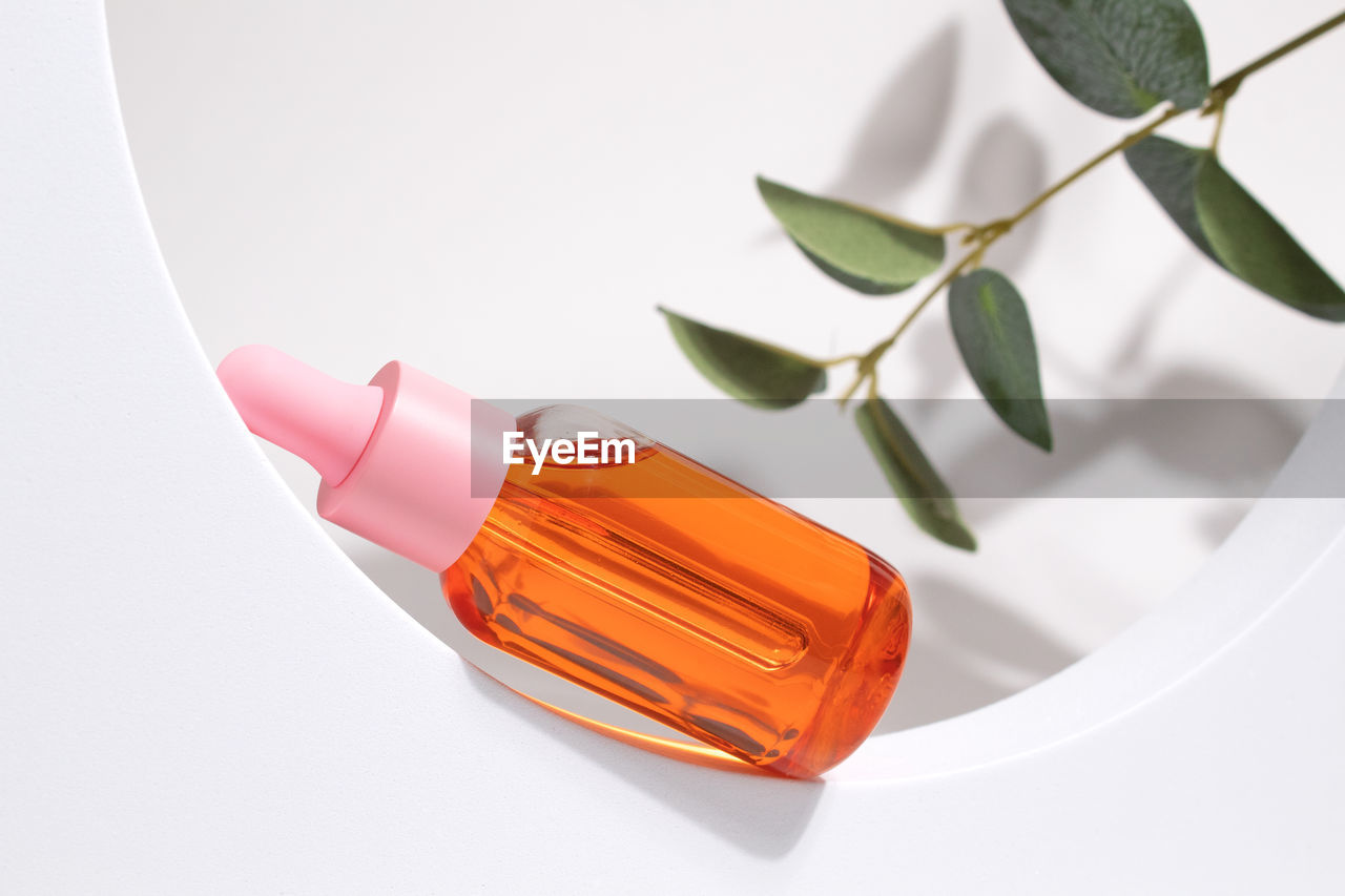 Glass cosmetic bottle with oil or serum for skin care on special podium on white background. 