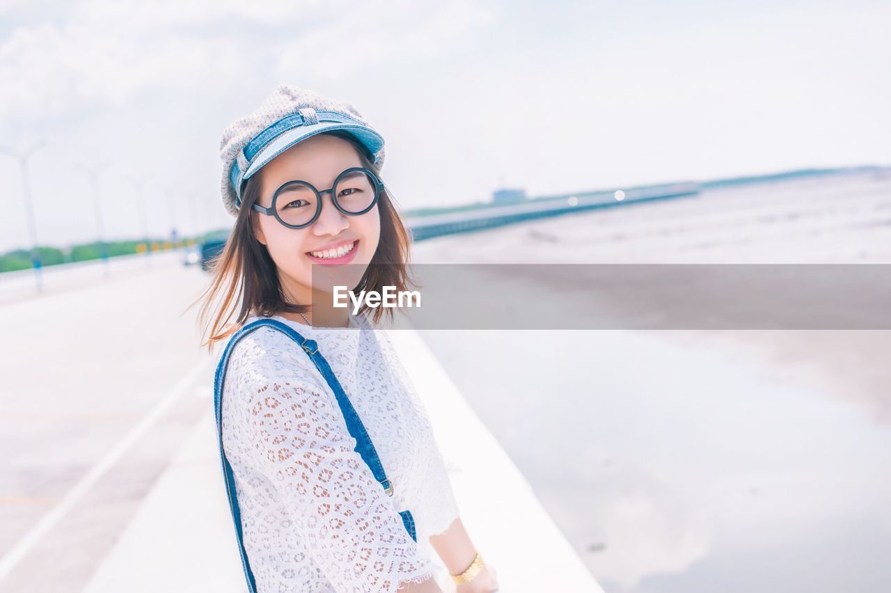 Portrait of smiling young woman standing at beach