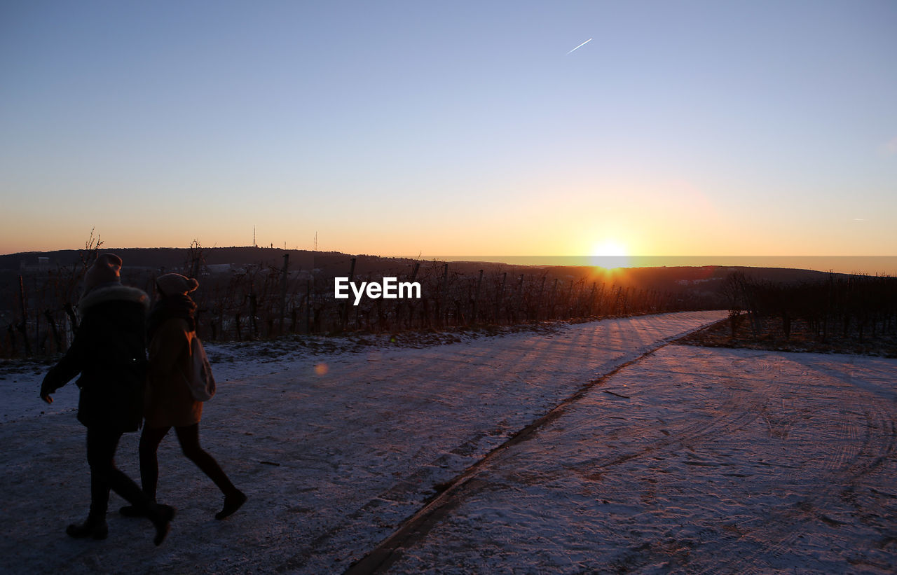 People walking in field during sunset