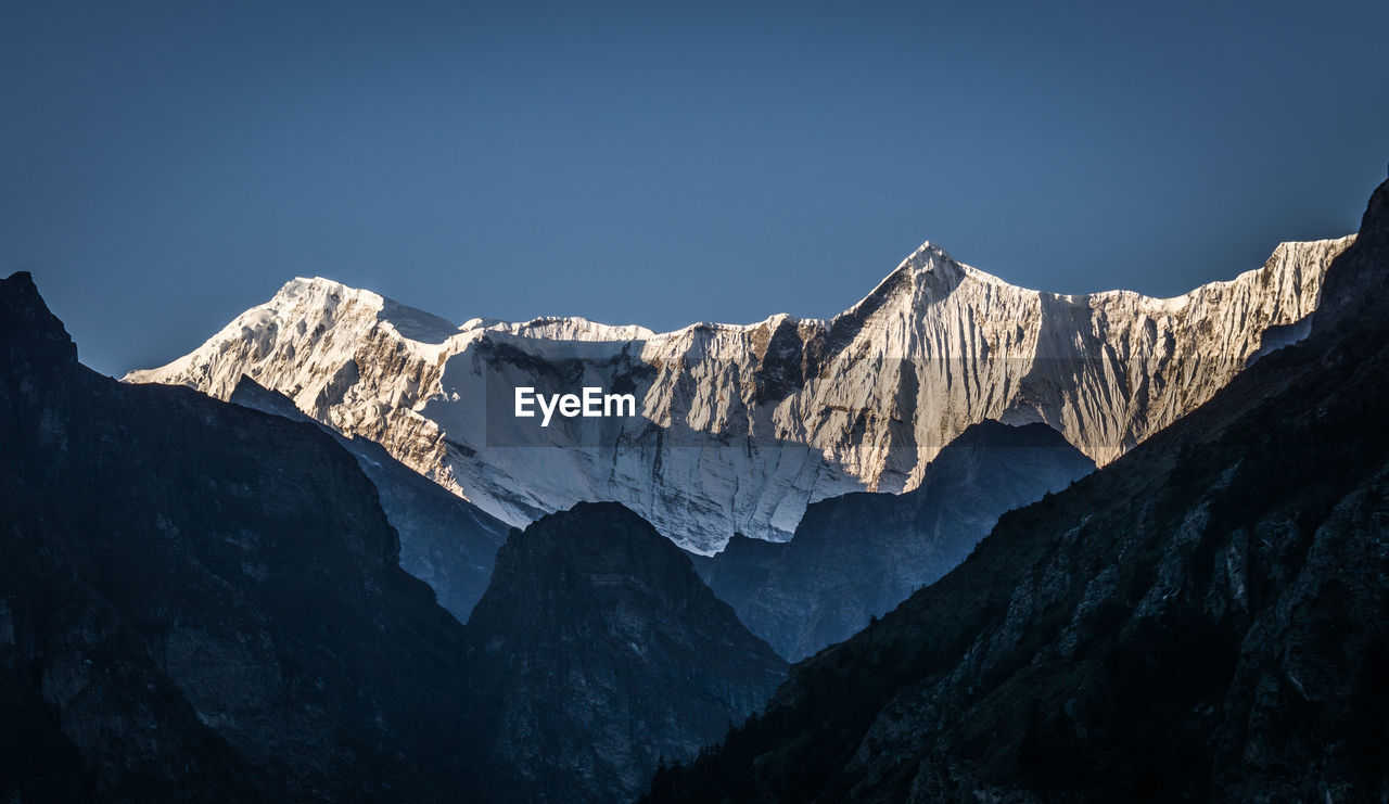 Scenic view of snowcapped mountains against clear sky