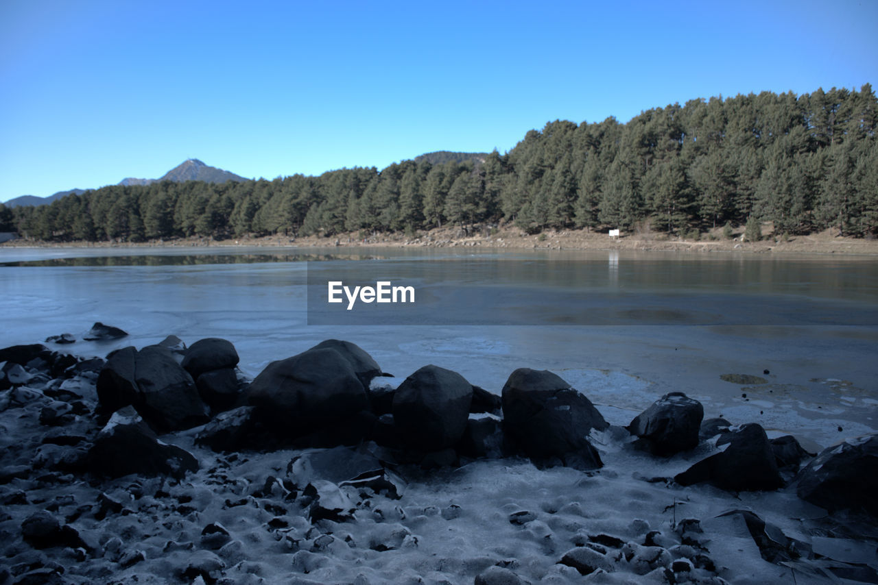 Scenic view of lake against clear sky during winter