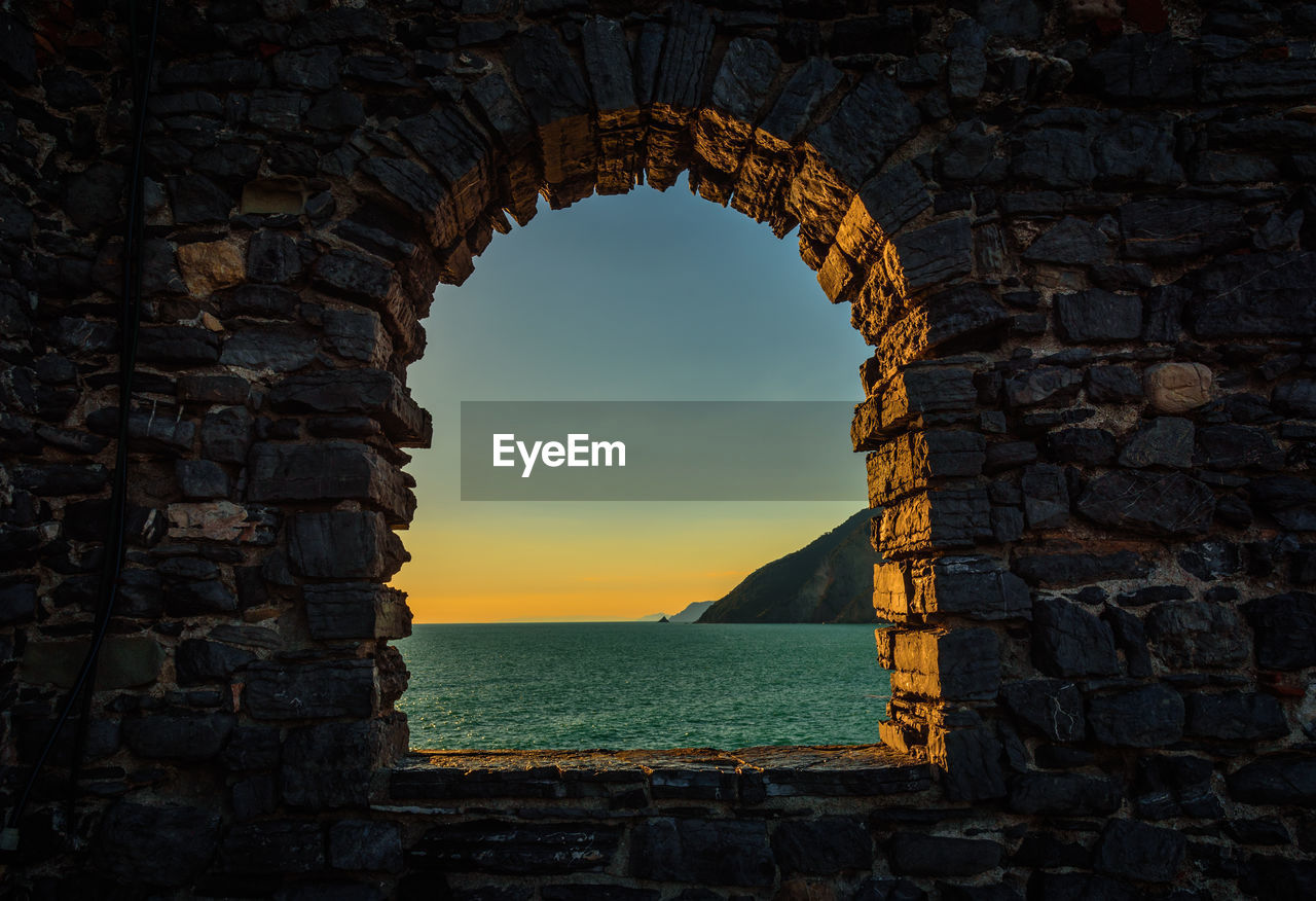 View of sea through arch window at sunset