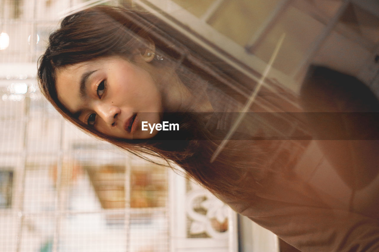 Portrait of young woman reflecting on glass