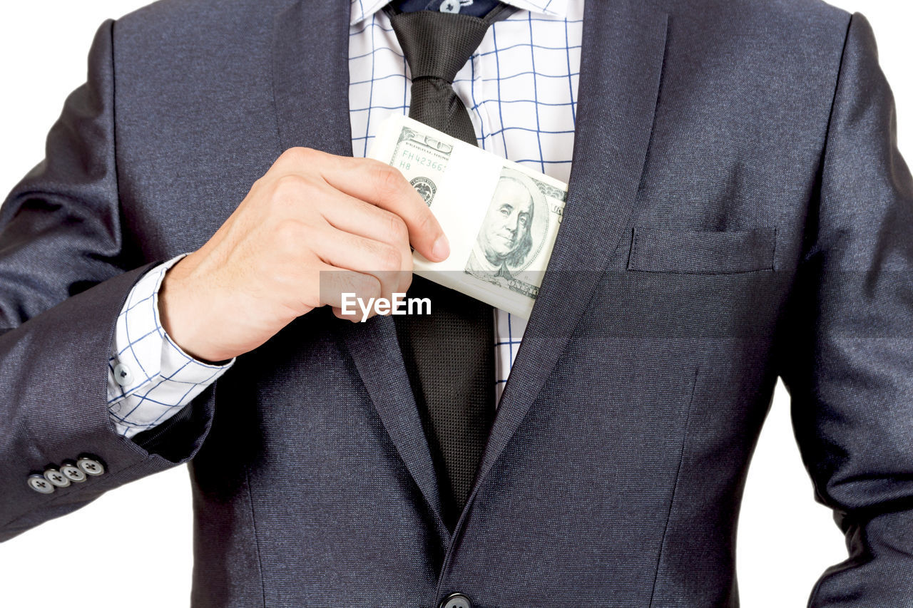 Midsection of businessman with paper currency against white background