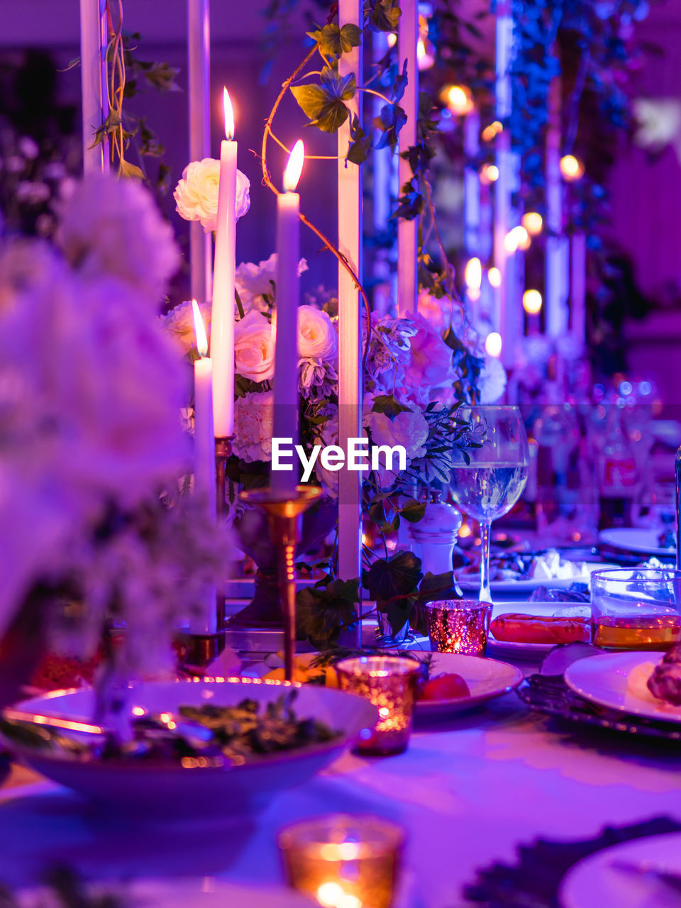 Table served for banquet with candles and floral compositions. 