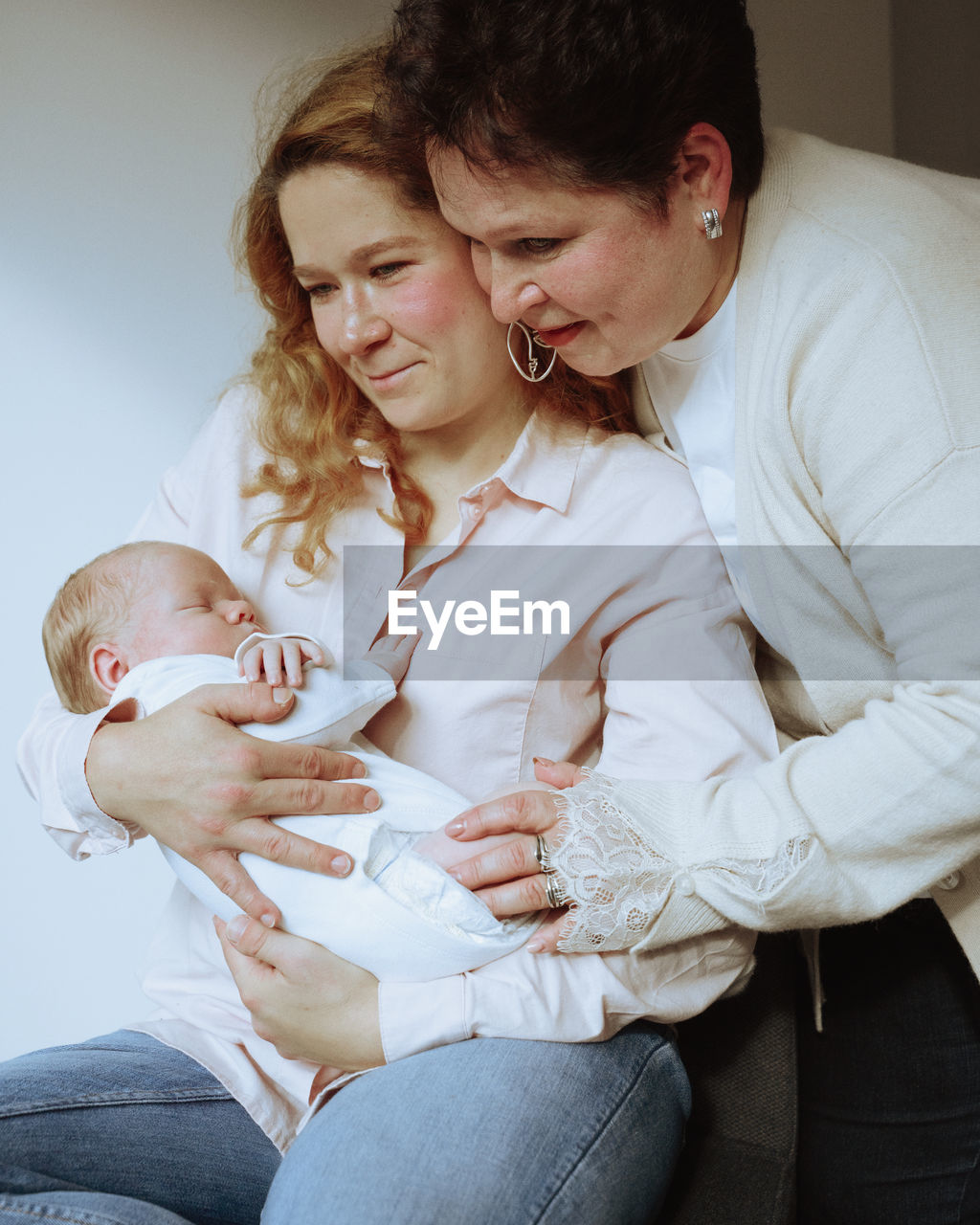 Mother and daughter holding a newborn baby at home