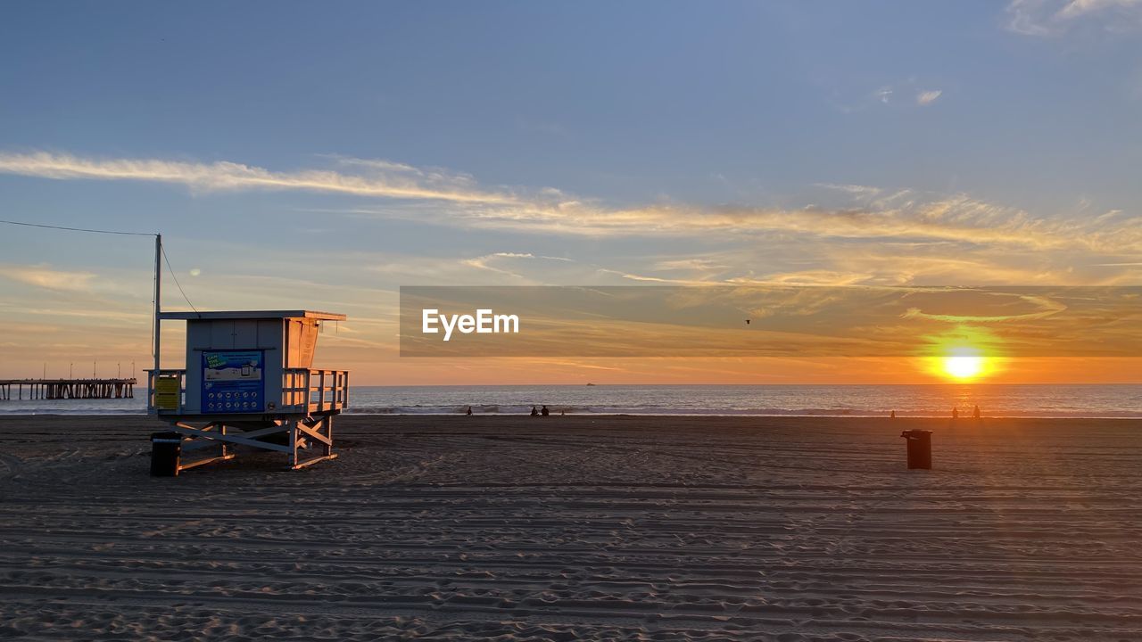 lifeguard hut on beach against sky during sunset