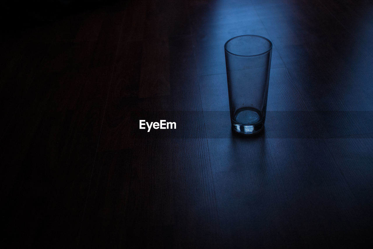 High angle view of empty drinking glass on hardwood floor