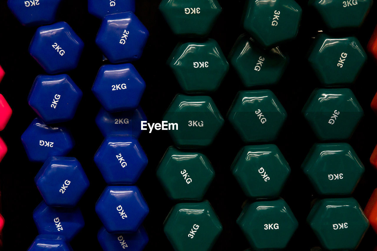 Full frame shot of numbers and text on dumbbells at gym