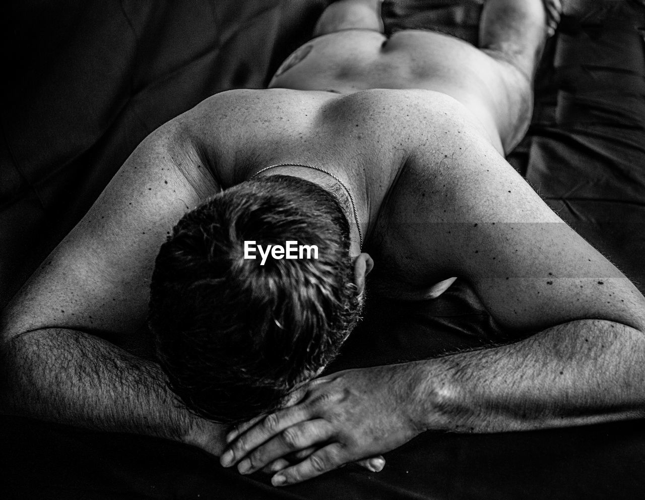 Full length of naked man lying on bed