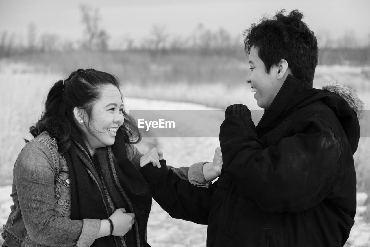 Cheerful siblings playing on field during winter