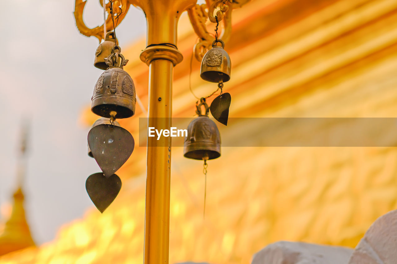 LOW ANGLE VIEW OF ELECTRIC LAMP HANGING AGAINST TEMPLE
