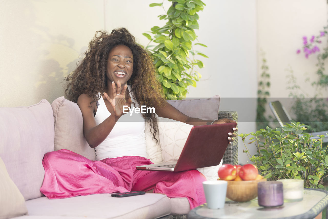 Mid adult woman using laptop while sitting on sofa at home