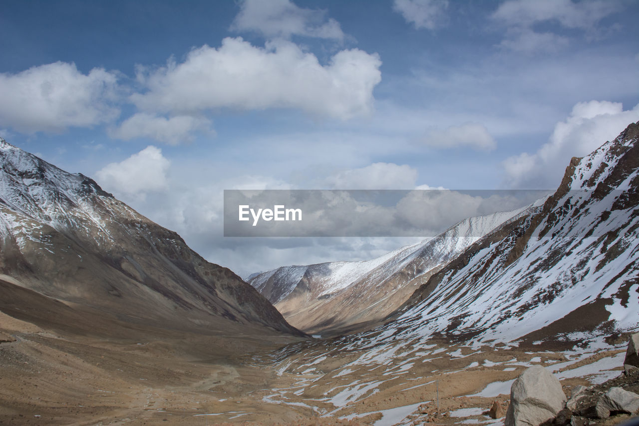 Scenic view of snowcapped mountains against cloudy sky