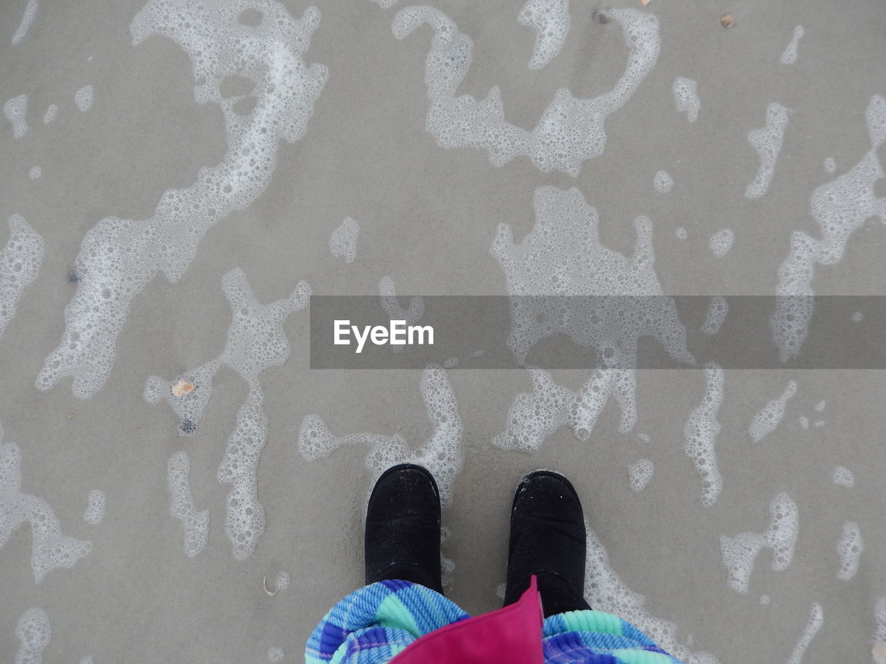 LOW SECTION OF PERSON STANDING ON SAND