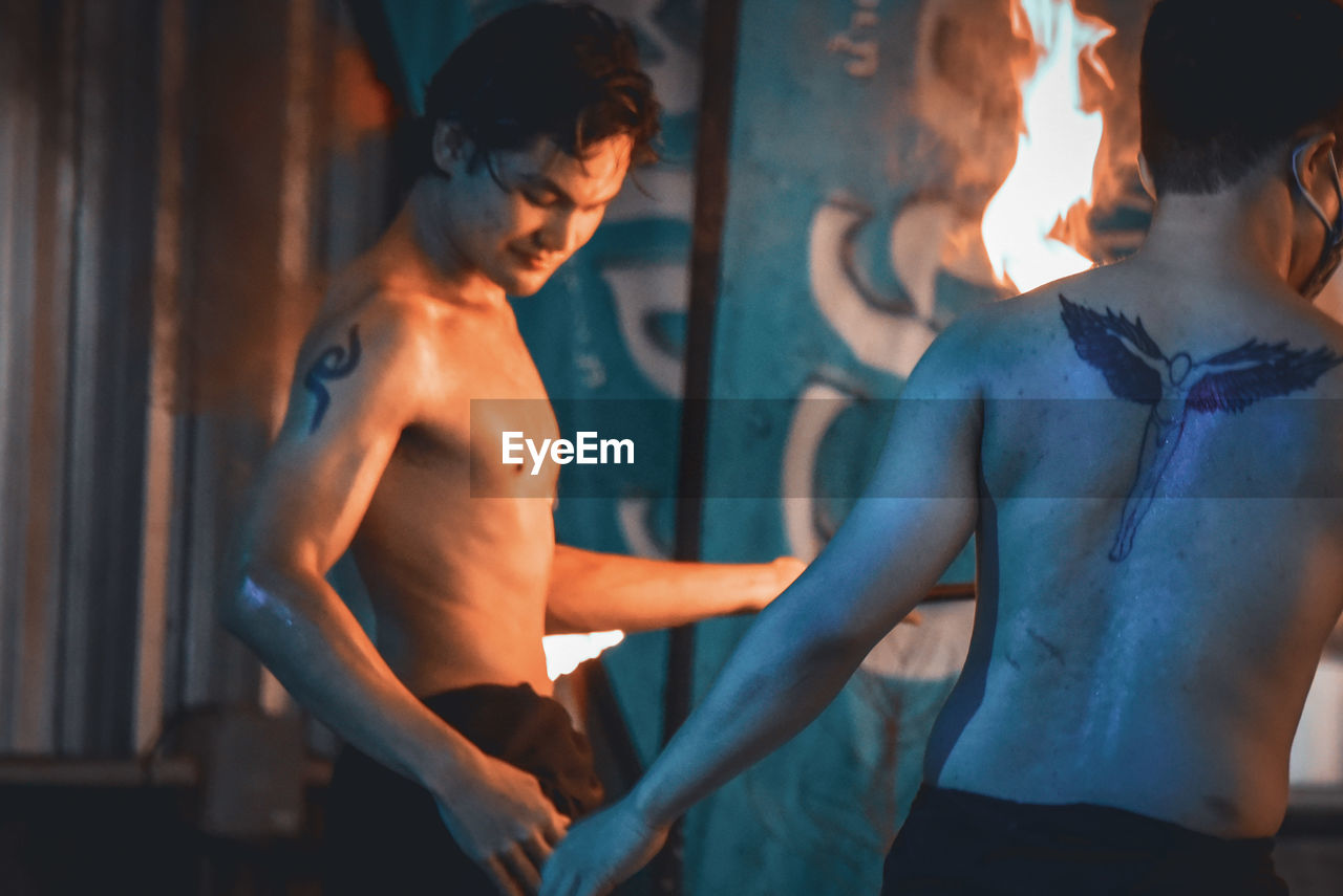 MIDSECTION OF SHIRTLESS MAN STANDING IN KITCHEN