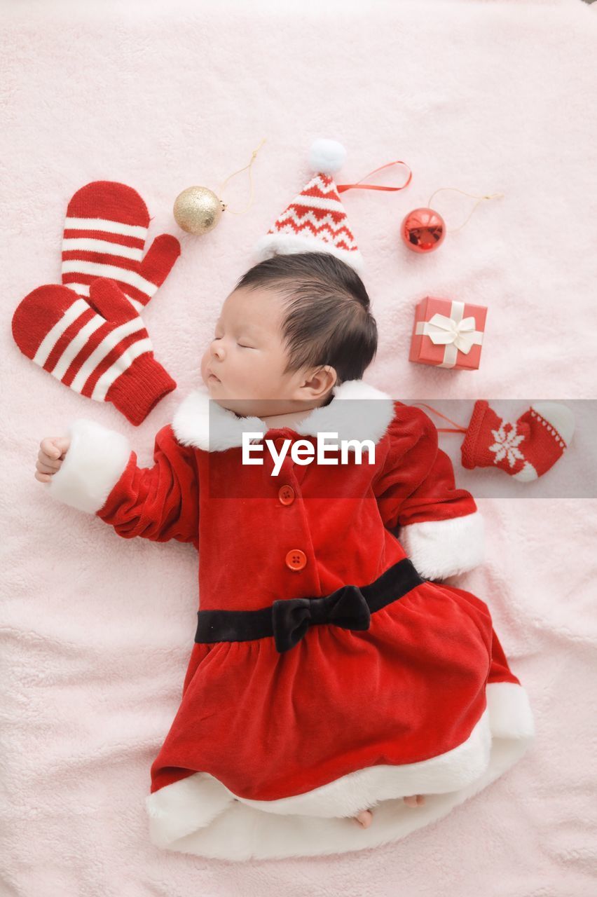 Directly above shot of baby girl wearing santa claus costume sleeping on bed at home