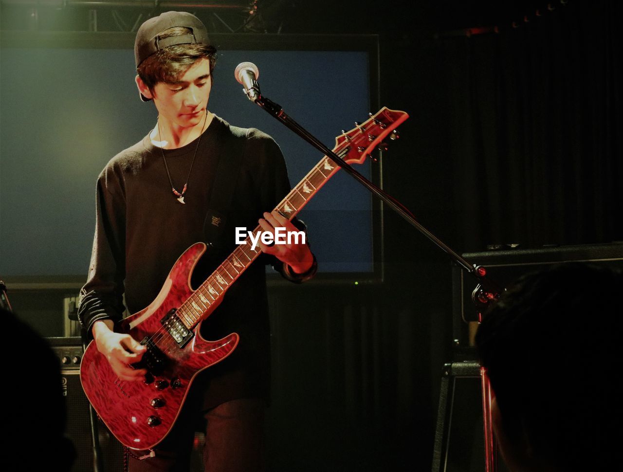 Teenage boy playing guitar during music concert 