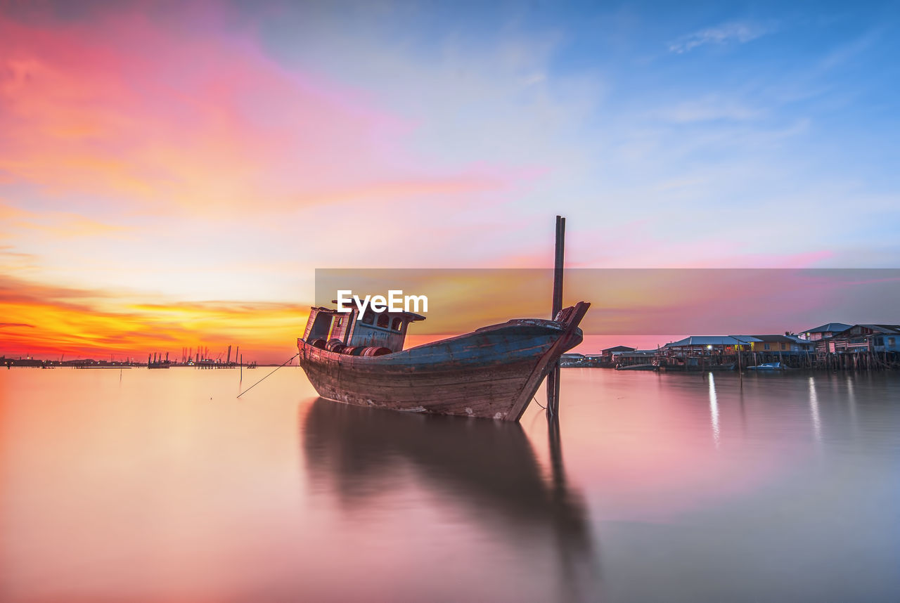 Boat moored on sea against sky during sunset