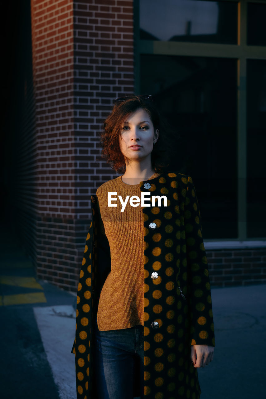 Portrait of woman standing against building