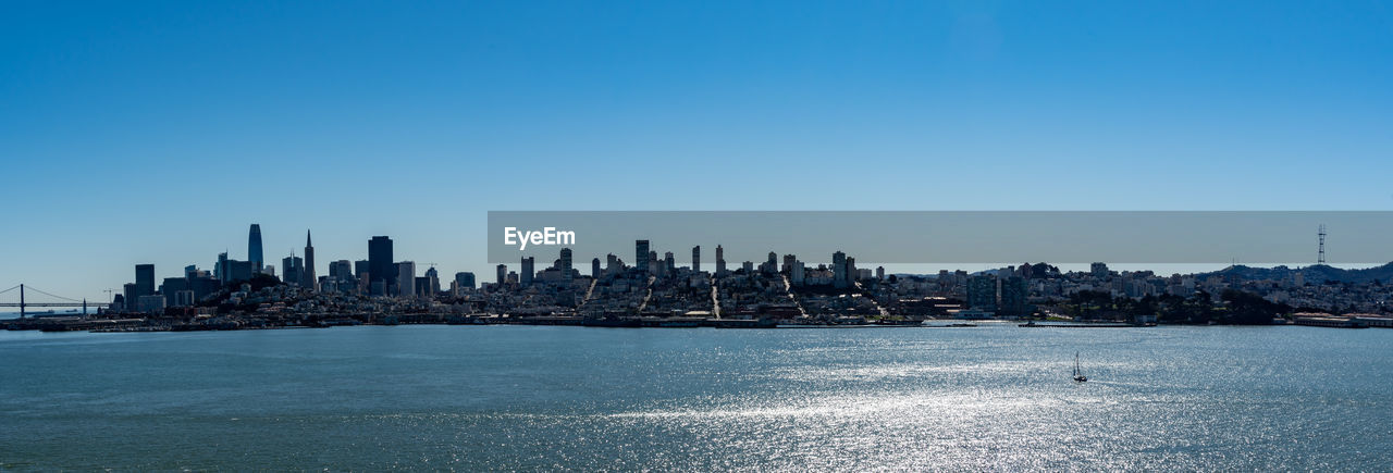 SEA BY BUILDINGS AGAINST CLEAR BLUE SKY