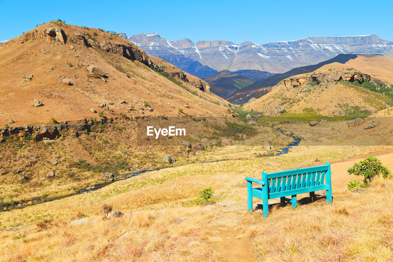 Scenic view of field and mountains against blue sky