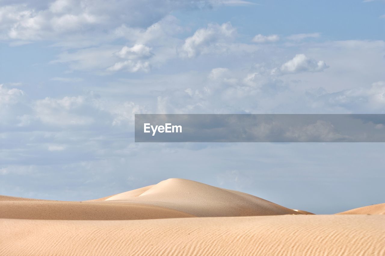 Sand dunes in desert against sky