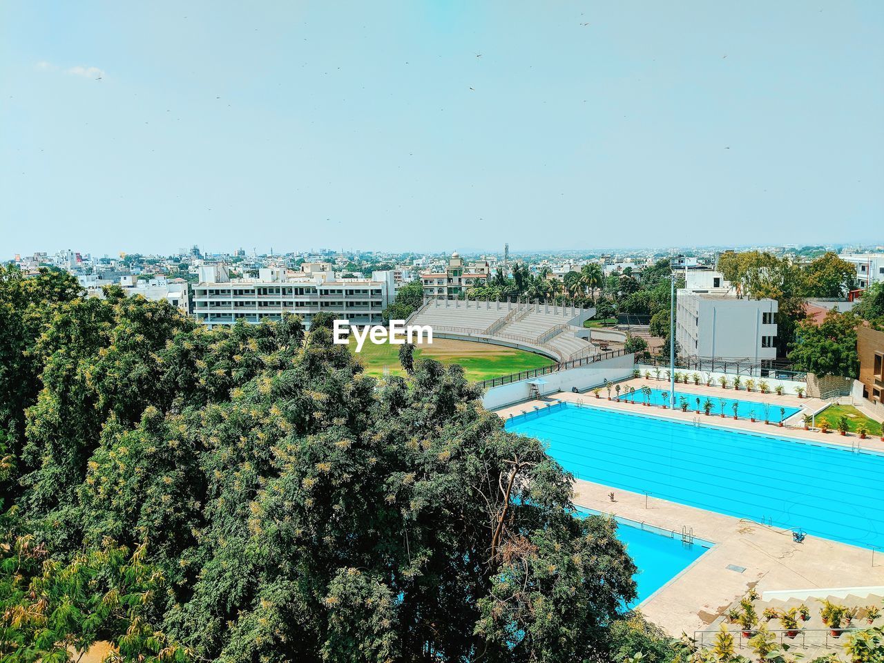 HIGH ANGLE VIEW OF SWIMMING POOL AGAINST BUILDINGS IN CITY