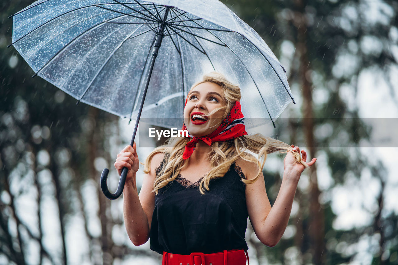 Woman holding umbrella standing during rainy season