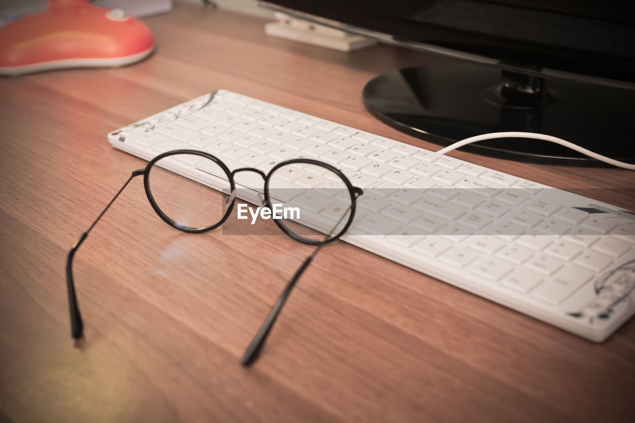 High angle view of computer keyboard with eyeglasses on table