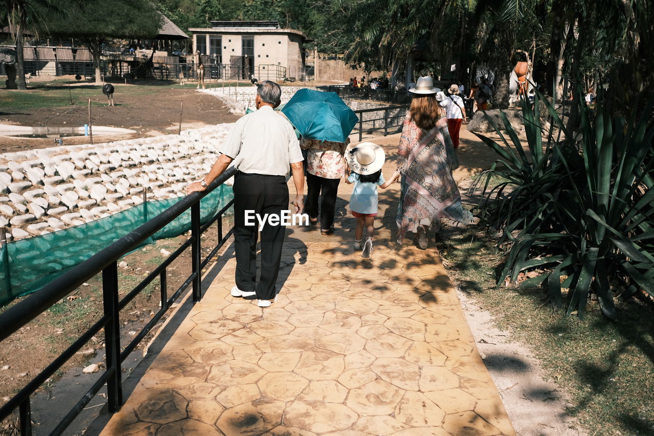 REAR VIEW OF PEOPLE WALKING OUTDOORS