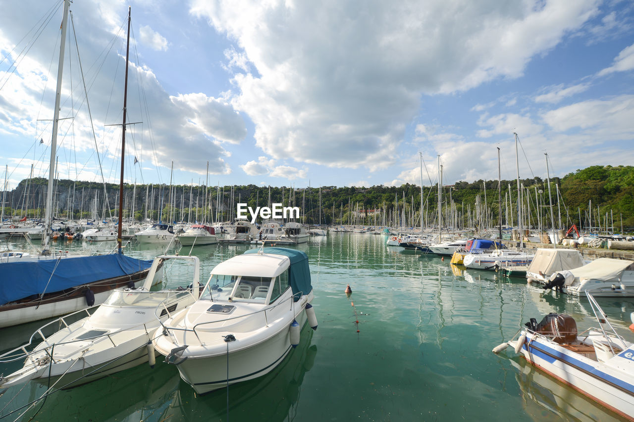 Boats moored at harbor against sky