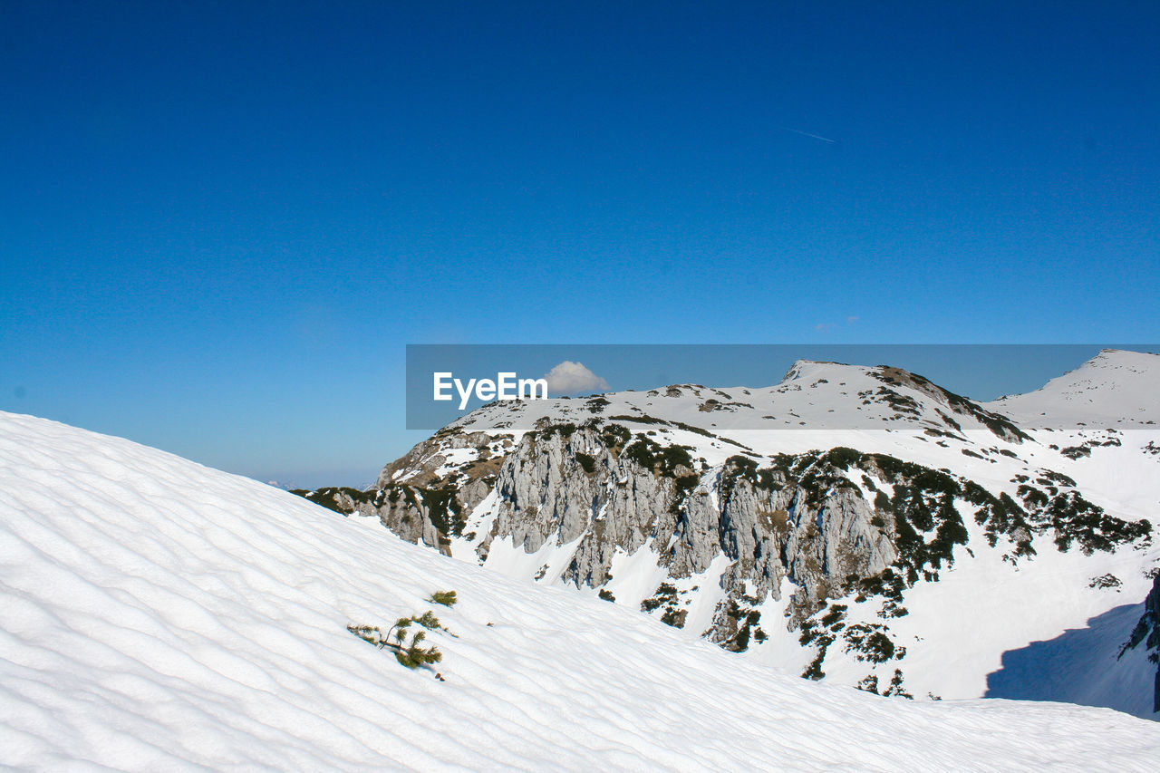 Scenic view of snowcapped mountains against clear blue sky