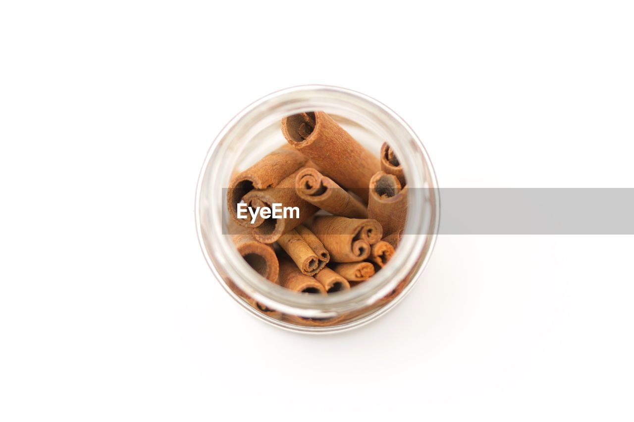 High angle view of cinnamons in jar over white background