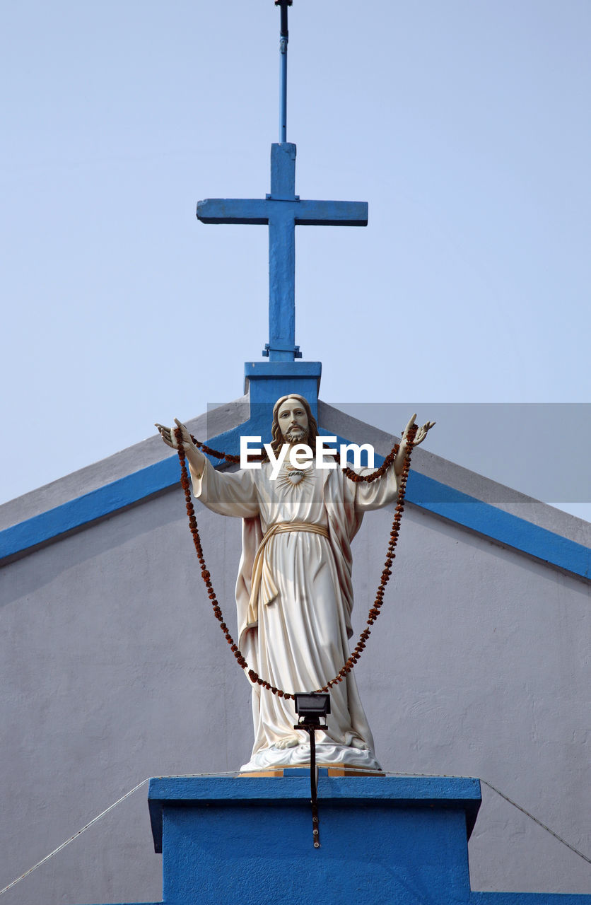 Low angle view of jesus christ statue by church against sky