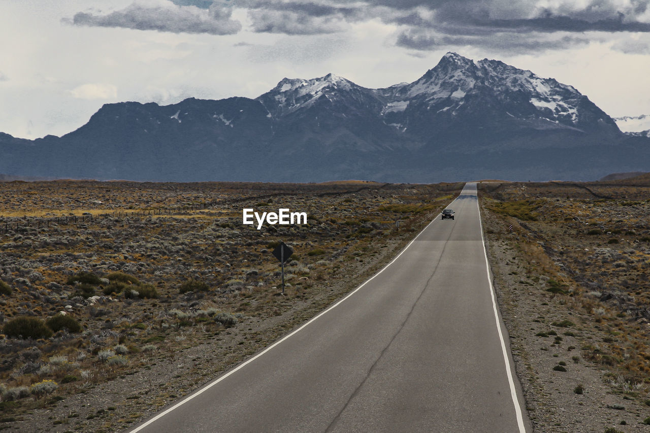 Road by snowcapped mountains against sky