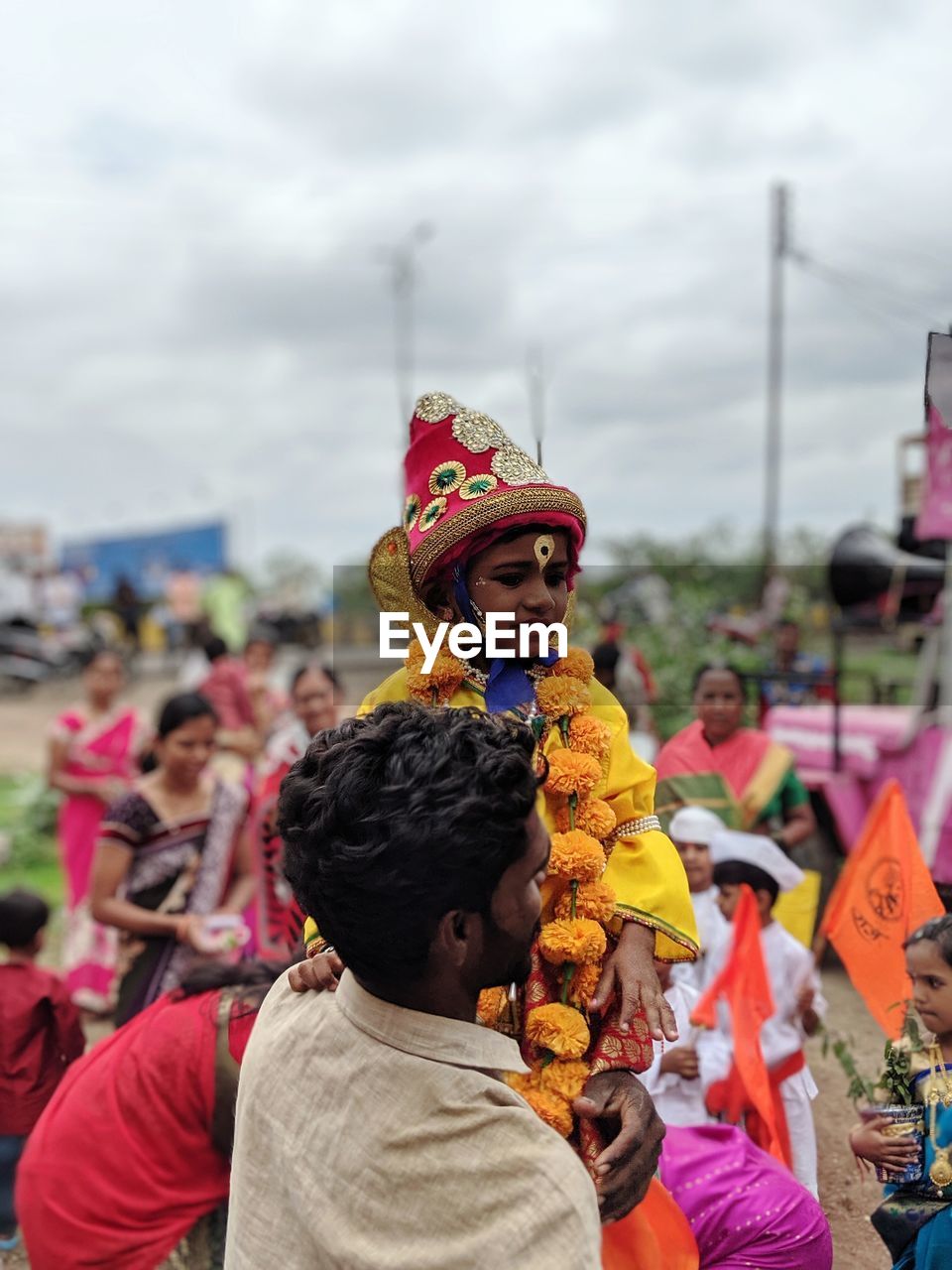 REAR VIEW OF PEOPLE WITH TOYS AGAINST SKY DURING FESTIVAL