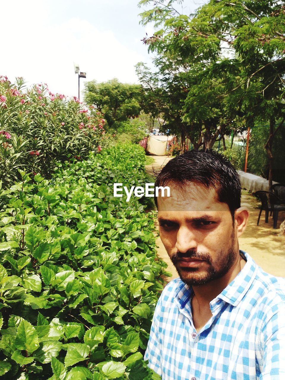 PORTRAIT OF MAN STANDING AGAINST TREES