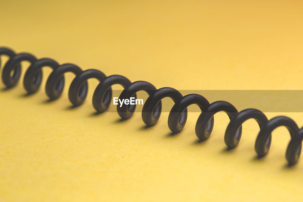 High angle view of spiral cable on yellow background