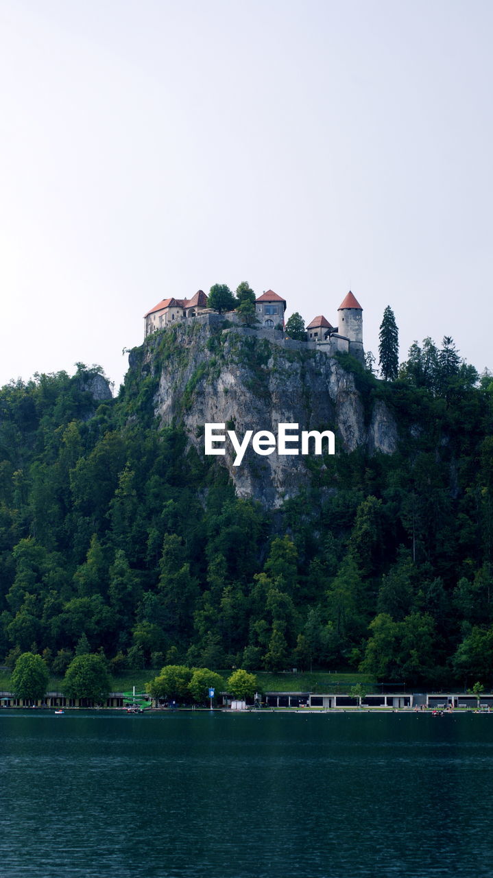 Lake in front of houses on rock mountains against clear sky