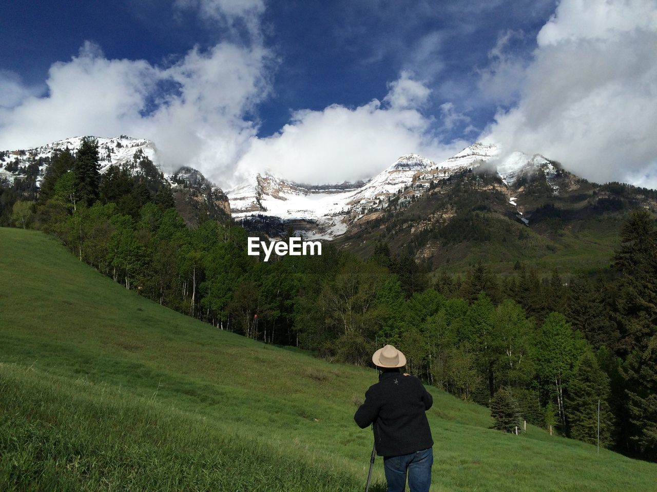 Rear view of man standing on green field against sky