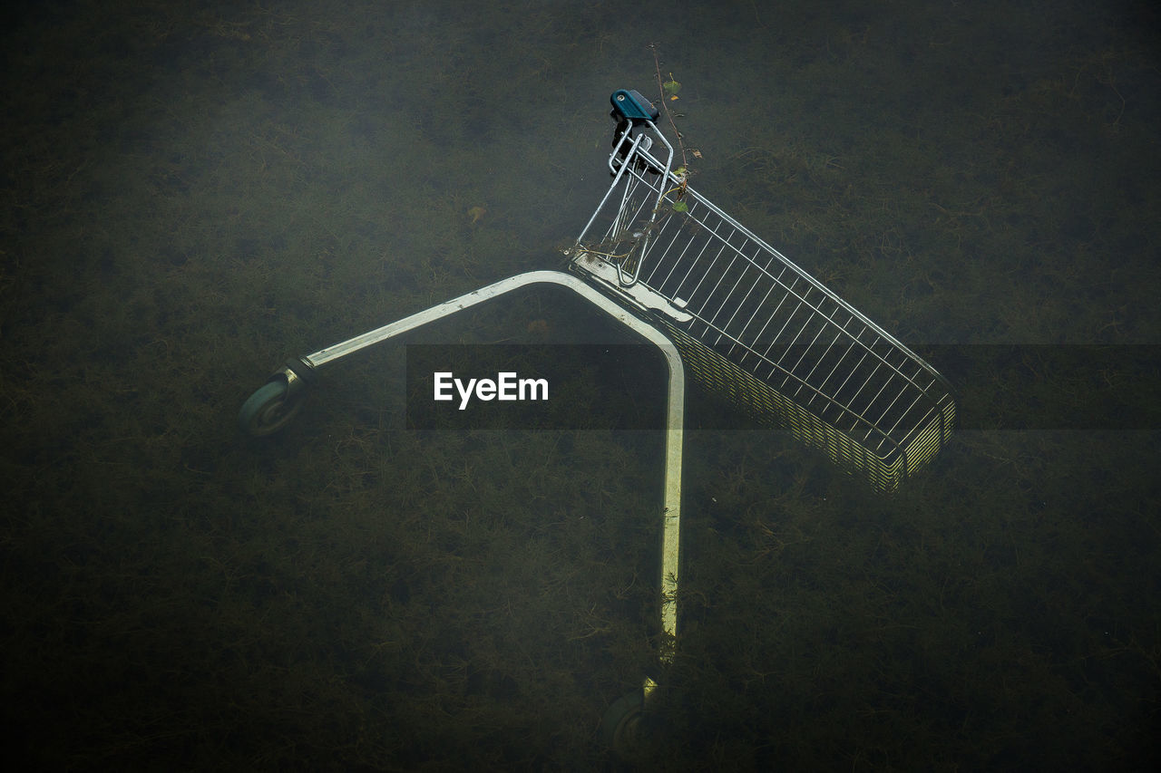 High angle view of shopping cart fallen in pond