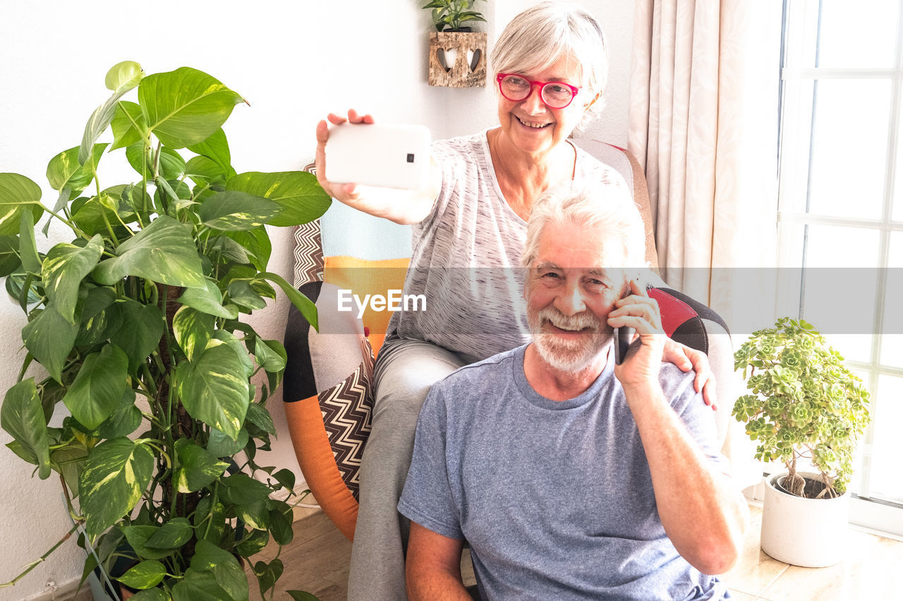 Smiling senior couple using mobile phones at home