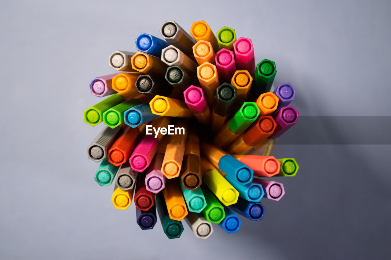 HIGH ANGLE VIEW OF MULTI COLORED PENCILS ON WHITE BACKGROUND