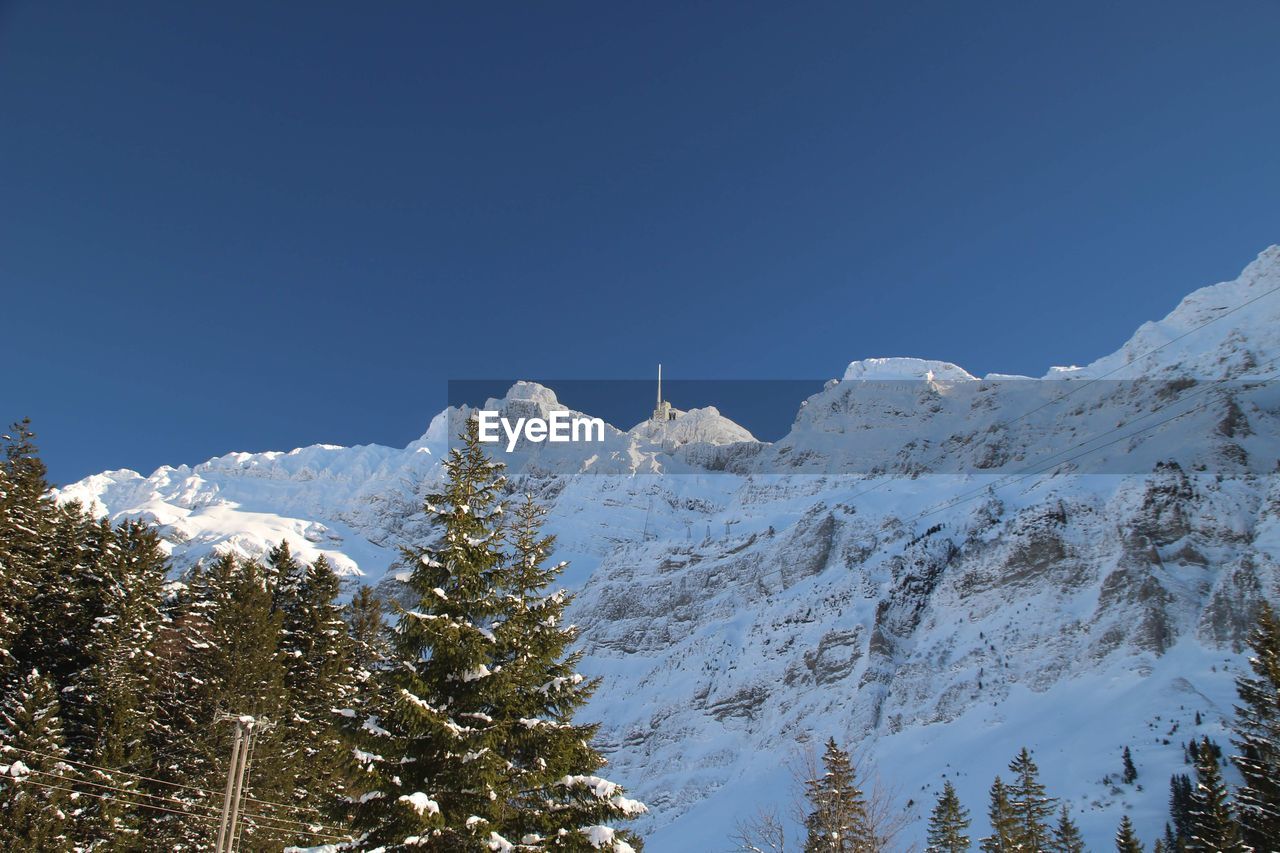 Low angle view of snowcapped mountains against clear sky