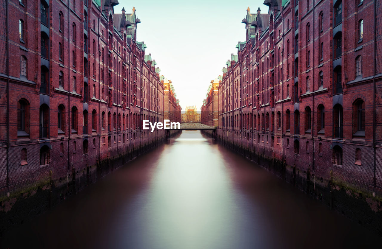 Canal amidst buildings against sky during sunset